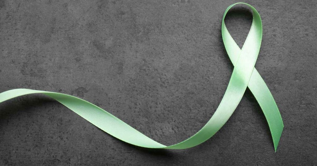 Green awareness ribbon on a dark textured background.