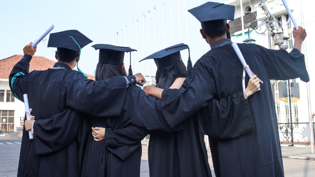 A group of people in graduation caps and gowns stand shoulder to shoulder
