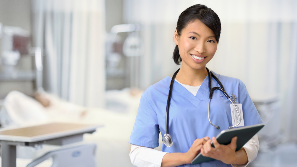 Healthcare professional smiling, holding tablet in hospital setting.