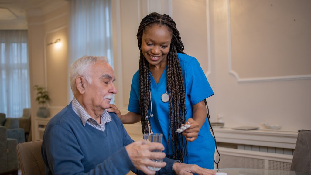 A caregiver helps a patient with his medication at a table