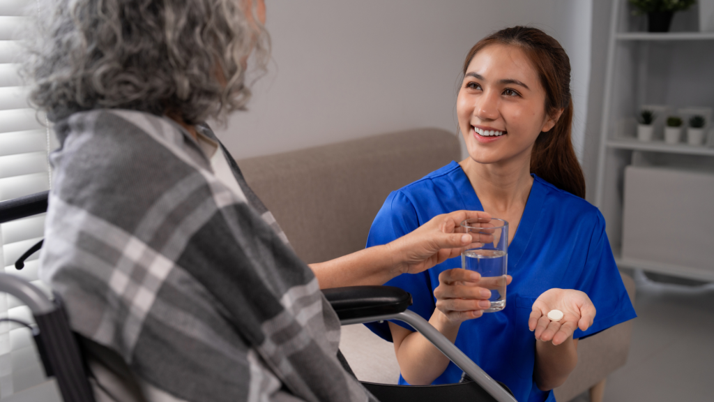 A smiling nursing assistant hold water and medication for a patient